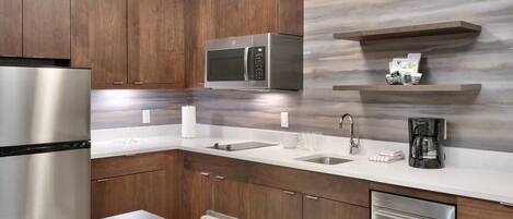A modern kitchen with wooden cabinets, stainless steel appliances, a marble backsplash, and a built-in dishwasher.