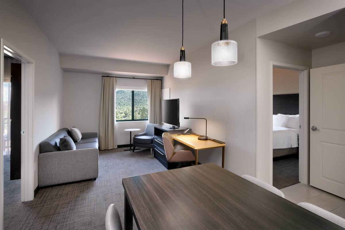 A hotel room with a sofa, a desk, a television, and a bed.