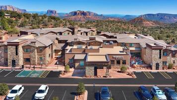 A hotel with a parking lot, multiple buildings, and a mountainous backdrop.