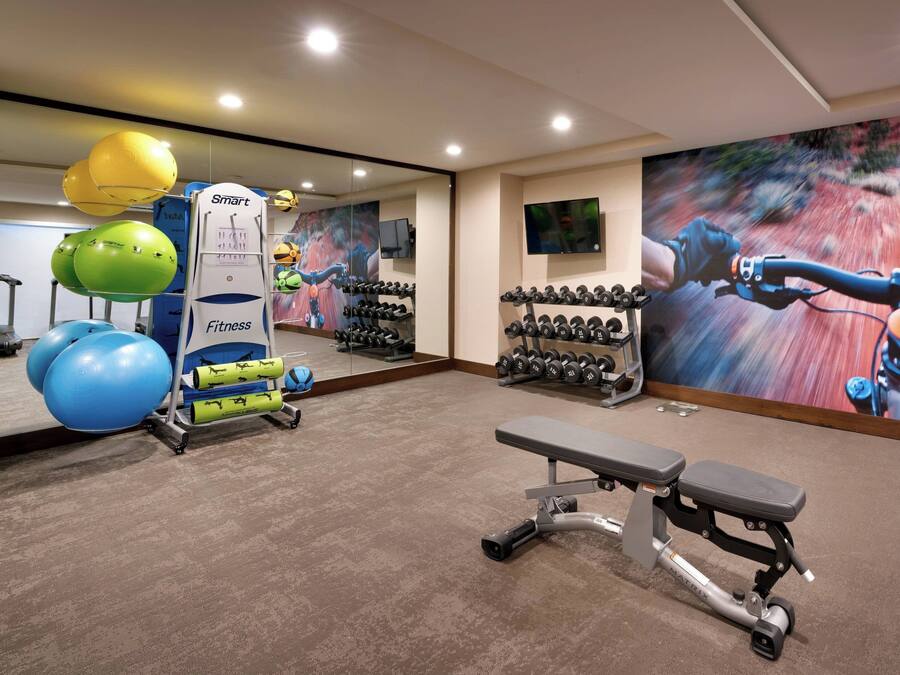 A gym with exercise equipment, a bench, and a mirror.