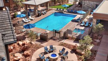 A rooftop pool area with a hot tub, lounge chairs, and umbrellas.