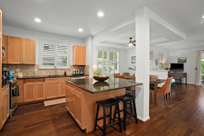 A modern kitchen with wooden cabinets, a central island, and a dining area with chairs.