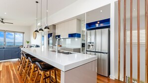 A modern kitchen with a central island, stainless steel appliances, and a bar area with stools.