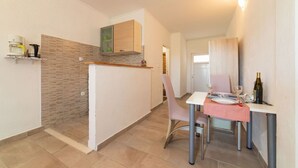 A compact kitchen with a dining area, a built-in oven, and a small dining table with chairs. - Studio Apartment with jaccuzzi (Kaštel Novi)