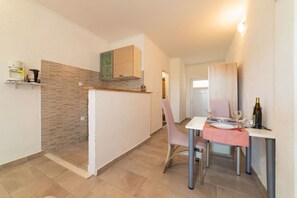 A compact kitchen with a dining area, a built-in oven, and a small dining table with chairs. - Studio Apartment with jaccuzzi (Kaštel Novi)