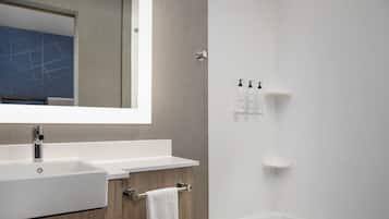 Un baño moderno con un espejo grande, un lavabo blanco, un perchero para toallas y una zona de ducha.