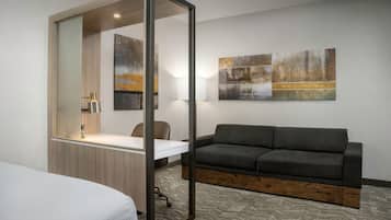 Una habitación de hotel moderna con cama, escritorio, sofá y dos cuadros abstractos en la pared.