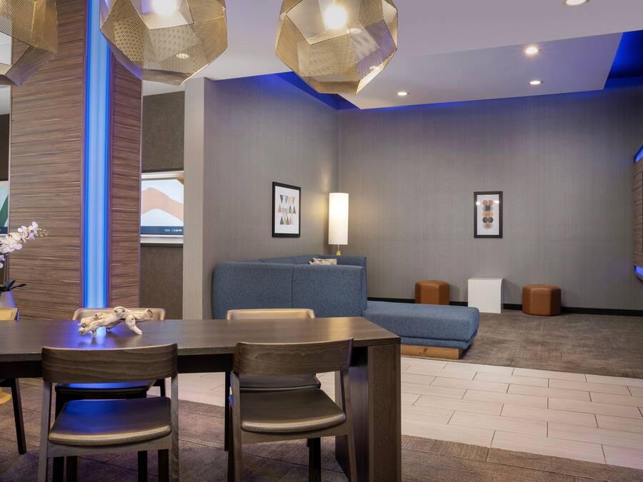 A modern hotel room with a dining area, a sofa, and a flat-screen TV.