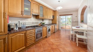 Une cuisine avec des meubles en bois, une cuisinière, un four à micro-ondes et un lave-linge.