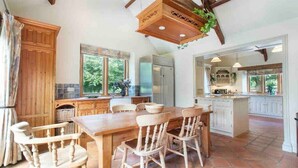A spacious kitchen with wooden cabinetry, a large island, and a dining area with chairs. - Stunning Country Farm House between Bristol & Bath (Bristol)