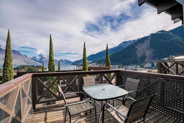 Une terrasse avec coin salon extérieur, offrant une vue sur un paysage montagneux et un lac.