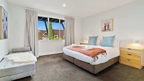 A bedroom with a bed, bedside tables, a chair, and a window with curtains.