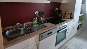 A modern kitchen with a stainless steel sink, a black stovetop, and a built-in oven. - Colmar Historic Center - BED'N BREDALA MAX - BookingAlsace (Colmar)