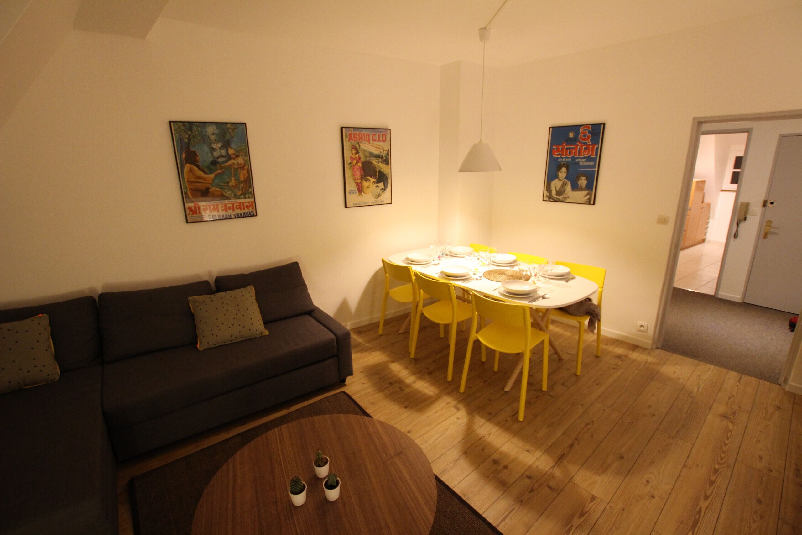 Un salon avec un canapé, une table à manger dressée pour quatre personnes et une petite table basse.