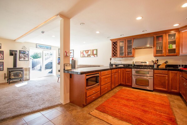 A modern kitchen with wooden cabinets, a built-in oven, and a large island with a microwave.