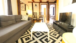 A living room with a sofa, a coffee table, a TV, and a patterned rug.