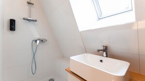 A modern bathroom with a shower, a sink, and a window.