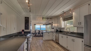 A modern kitchen with white cabinets, stainless steel appliances, and a view to the sea. - Belleview's Beauty - Lakefront - TLUXP (Homewood)