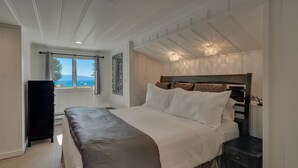 A bedroom with a large bed, a nightstand, a dresser, and a window with a view of the sea. - Belleview's Beauty - Lakefront - TLUXP (Homewood)