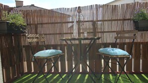 An outdoor seating area with a table and two chairs, surrounded by a bamboo fence and potted plants. - Colmar City Center - Appartement SCHNAPSALA - BookingAlsace (Colmar)
