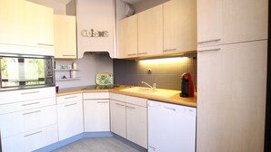 A modern kitchen with white cabinets, a built-in oven, a dishwasher, and a sink. - Colmar City Center - Appartement SCHNAPSALA - BookingAlsace (Colmar)