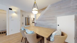 A modern kitchen with white cabinets, stainless steel appliances, and a wooden dining table with chairs. - Lovely, 2 bedroom / 2 bathroom, Villas Foxglove townhome short walk to the slope (Whistler)