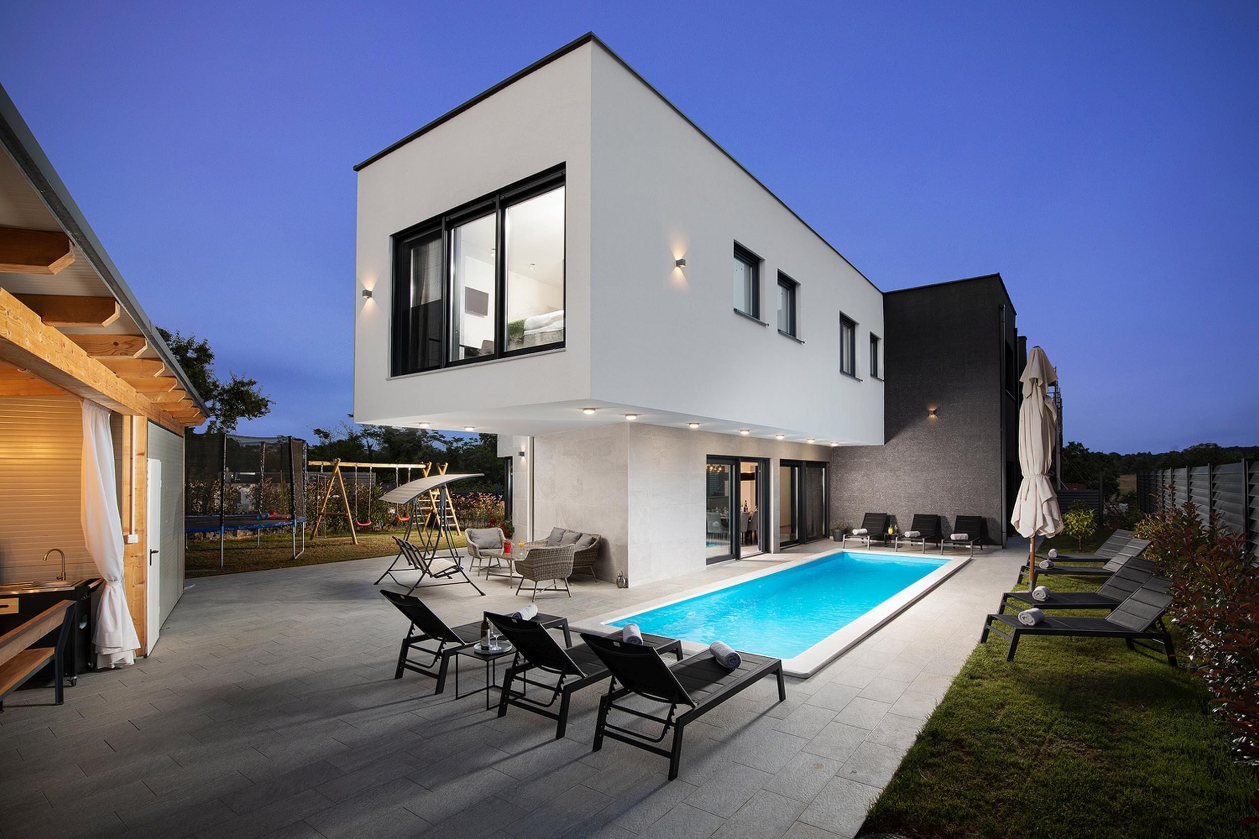 Uma casa moderna de dois andares com piscina, área de estar externa e gramado bem cuidado.