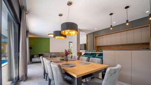A modern dining area with a wooden table, grey upholstered chairs, and pendant lighting. - Villa Tiki with pool heating inclusive (Medulin)