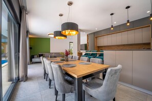 A modern dining area with a wooden table, grey upholstered chairs, and pendant lighting.