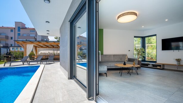 A modern living room with a pool, large windows, and a flat-screen TV. - Villa Tiki with pool heating inclusive (Medulin)