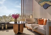 A modern living room with a sofa, a round wooden table, and a vase with pink flowers.