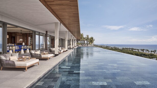 A modern infinity pool with a view of the ocean, outdoor seating with cushions, and a wooden ceiling. - Regent Phu Quoc (Phu Quoc)