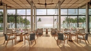 A spacious indoor area with large windows overlooking a beach, furnished with multiple seating arrangements and a central table. - Regent Phu Quoc (Phu Quoc)