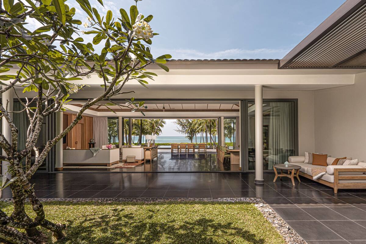A modern outdoor living area with a patio, seating, and a view of the ocean.