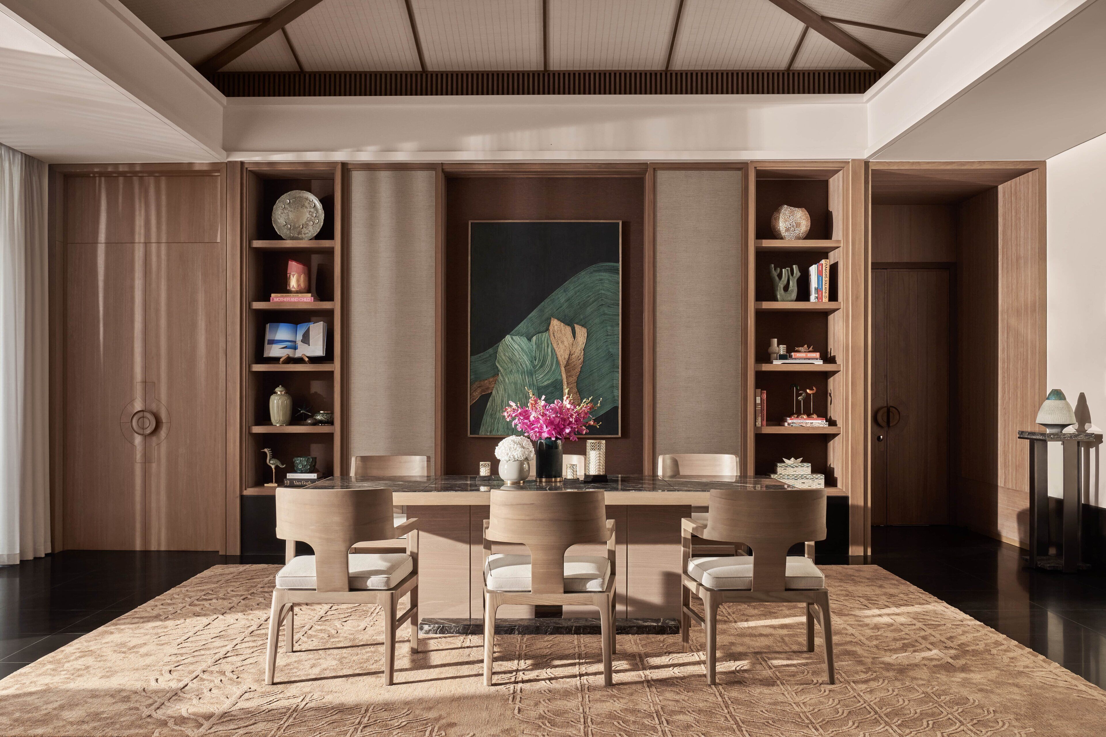 A modern dining area with a central table, chairs, and a large painting.