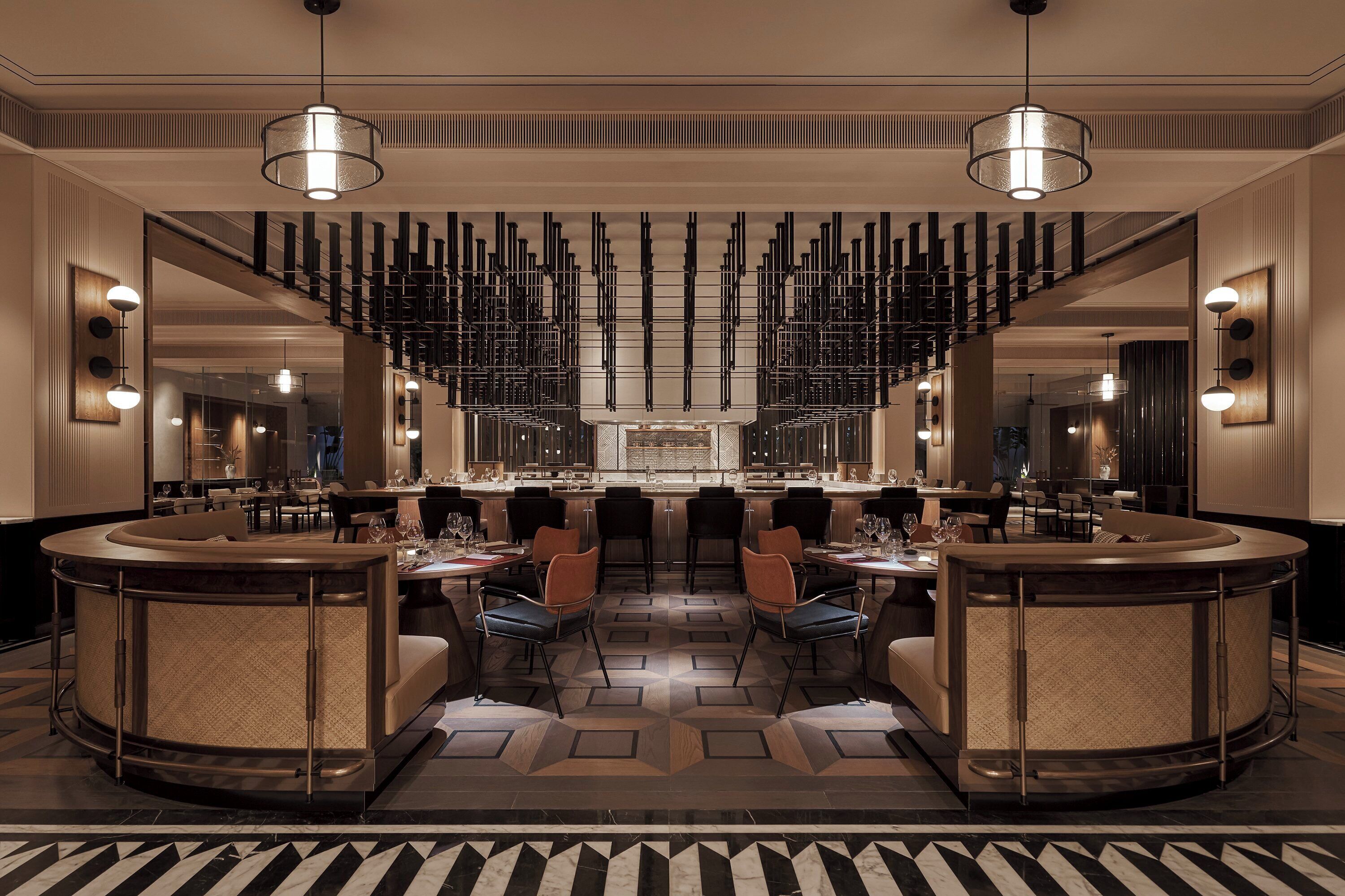 Een moderne hotel lobby met een centrale bar, zithoeken en een vloer met een patroon.