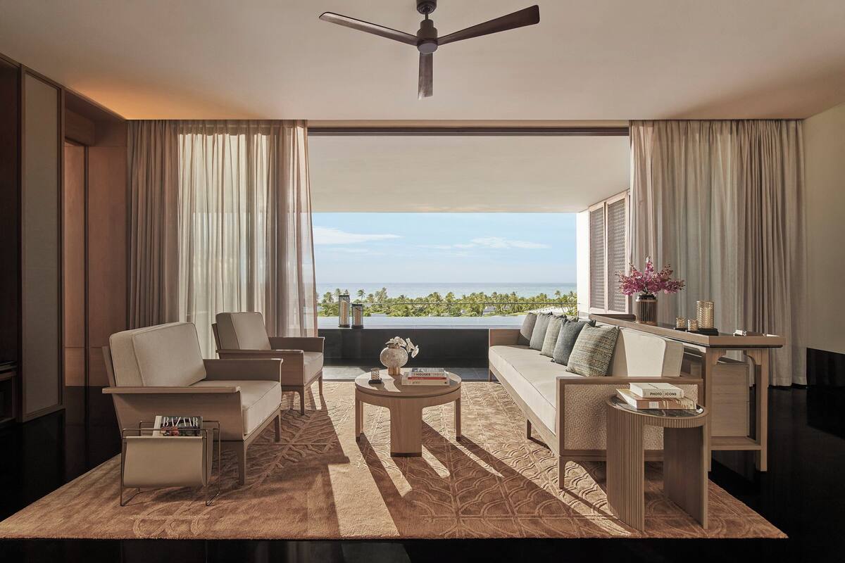 A modern living room with a sofa, chairs, a coffee table, and a view of the ocean.