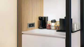 Eine moderne Küchenzeile mit Holzpaneelen, einer Glasablage, einer Kaffeemaschine und einem Kaffeemühle.