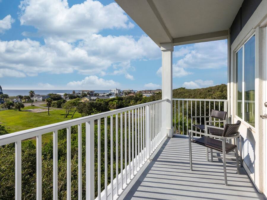 En balkon med udsigt over havet og en græsplæne.