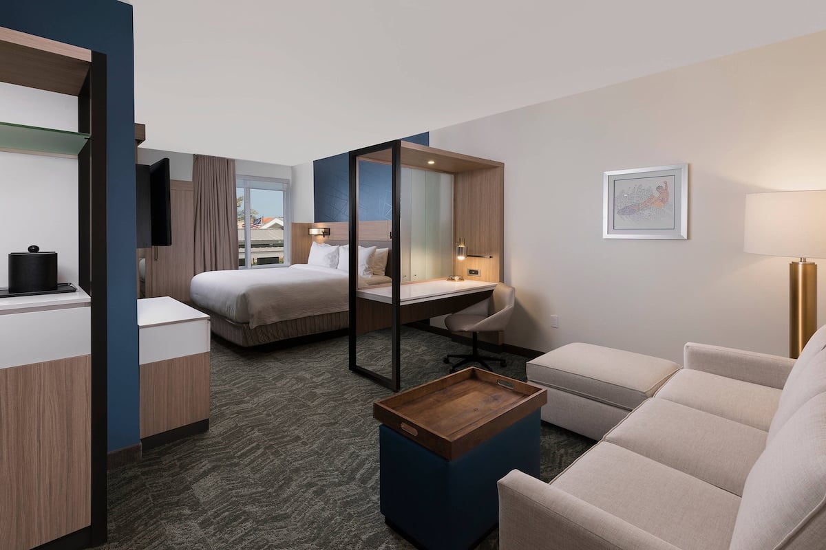 A hotel room with a bed, desk, chair, and a small wooden table.