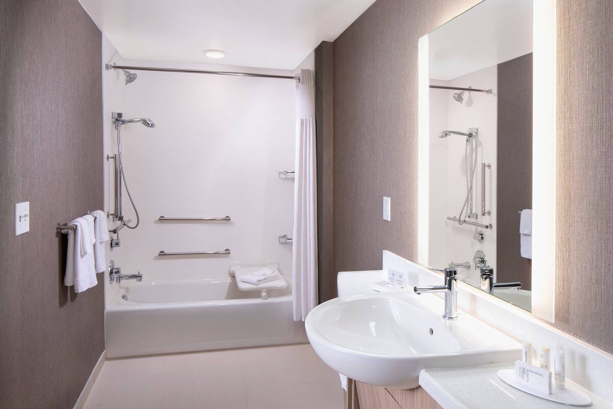 A modern bathroom with a bathtub, a large mirror, and a sink.