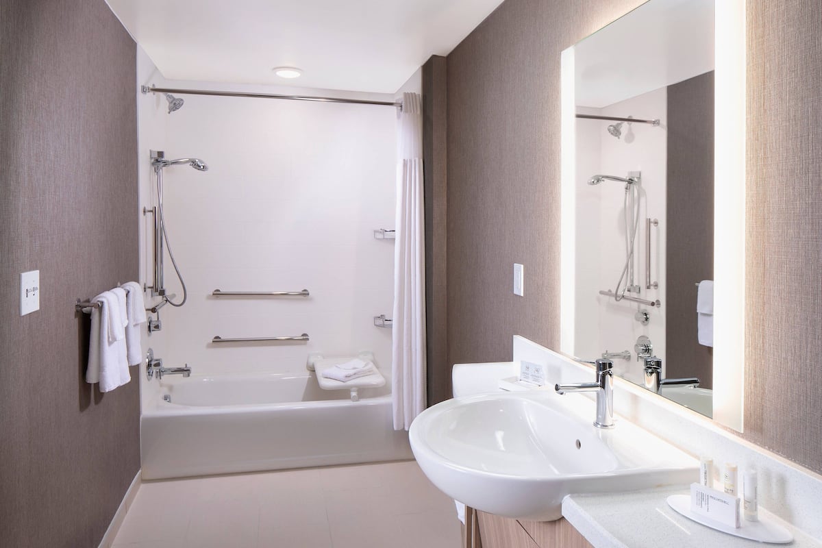 A modern bathroom with a bathtub, a large mirror, and a sink.
