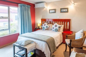 A bedroom with a bed, bedside table, lamp, and a chair.