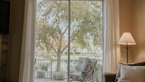 A room with a large sliding glass door leading to an outdoor area with a chair and table. There is a sofa and a lamp in the room. - Waterfront Mesa Gilbert First Floor Gated Condo Golf Updated Clean Quiet (Mesa)