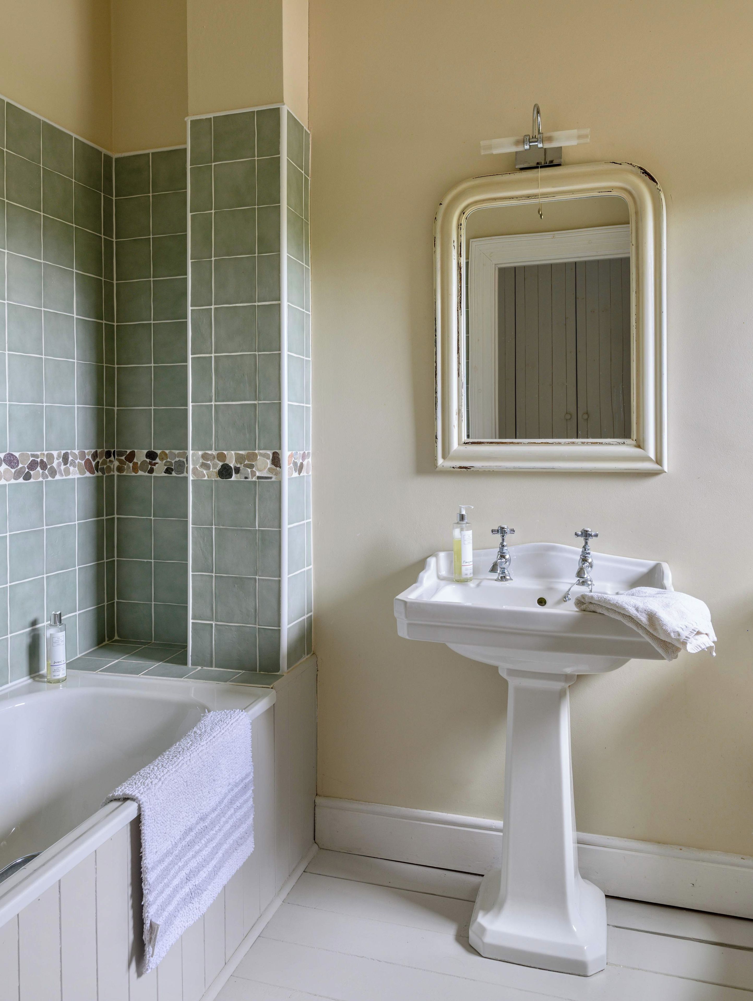 Un baño con bañera, lavamanos y espejo.