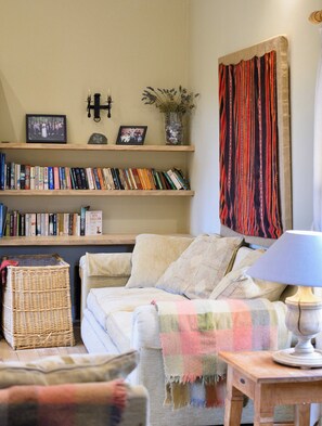 Un salon chaleureux avec un canapé, une lampe, une bibliothèque remplie de livres et une décoration murale.