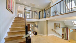 Un intérieur spacieux avec un escalier en bois, un balcon au deuxième étage et une vue sur l  ’extérieur.
