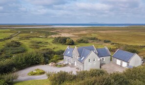 Ein Steinhaus mit einem Schotterweg und Blick auf das Meer.