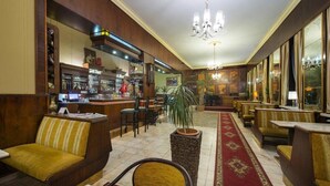 Um saguão de hotel com área de bar, espaços de estar e um candelabro.