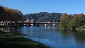 A river with a bridge, trees, and a forested hill in the background. - -- Diligence -- (Aire-sur-l'Adour)